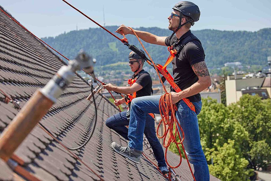 Deux ouvriers spécialisés sur un toit en pente avec un système de retenue et d'arrêt INNOTECH