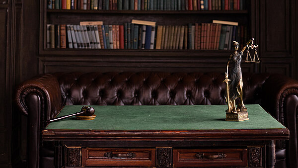 Una figura y un mazo de juez ilustran las normativas legales para sistemas anticaída