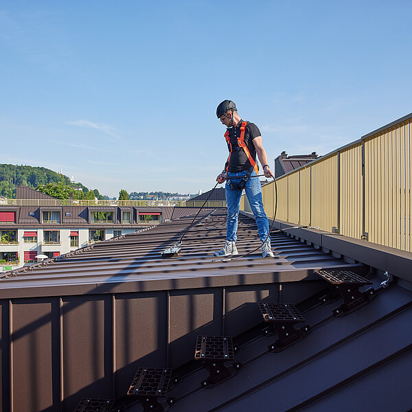 Un homme sur un toit en tôle avec différentes hauteurs de chute.