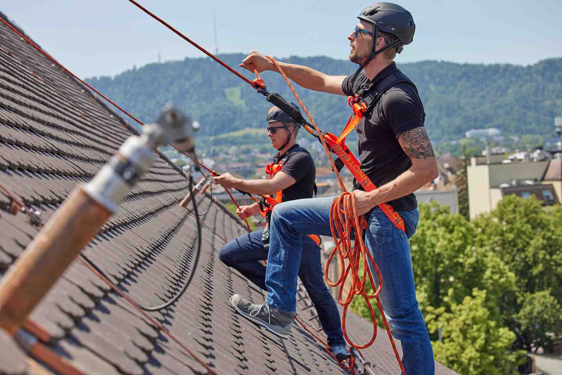 Dos trabajadores cualificados en un tejado inclinado con un sistema de retención y anticaídas INNOTECH